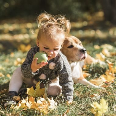 girl-playing-with-ball-sitting-grass-near-her-dog-park